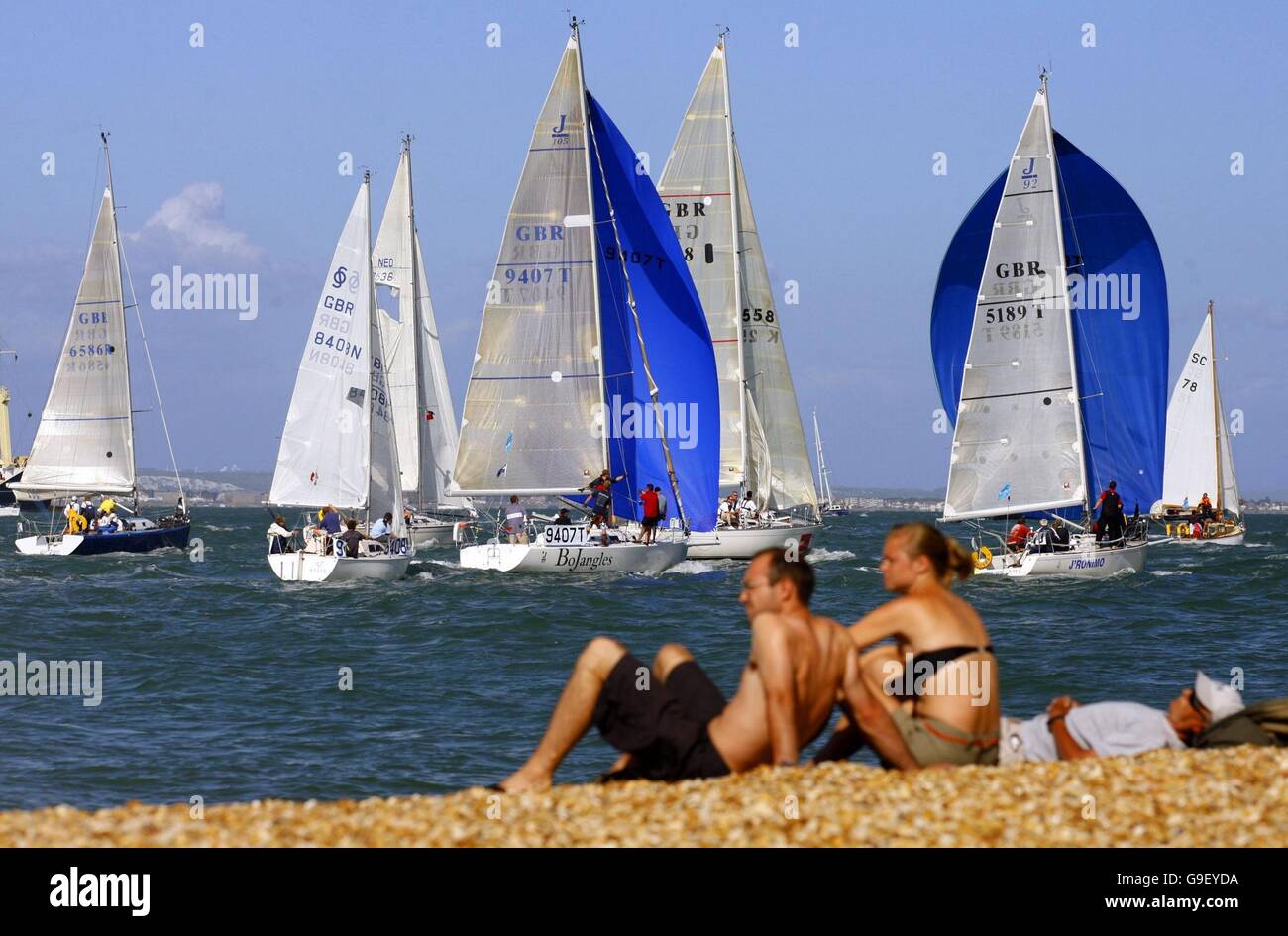 Gli spettatori sulla spiaggia a Cowes sull'Isola di Wight guardare le barche di ritorno dalla racing su Solent il secondo giorno della Skandia Cowes Week regata. Foto Stock