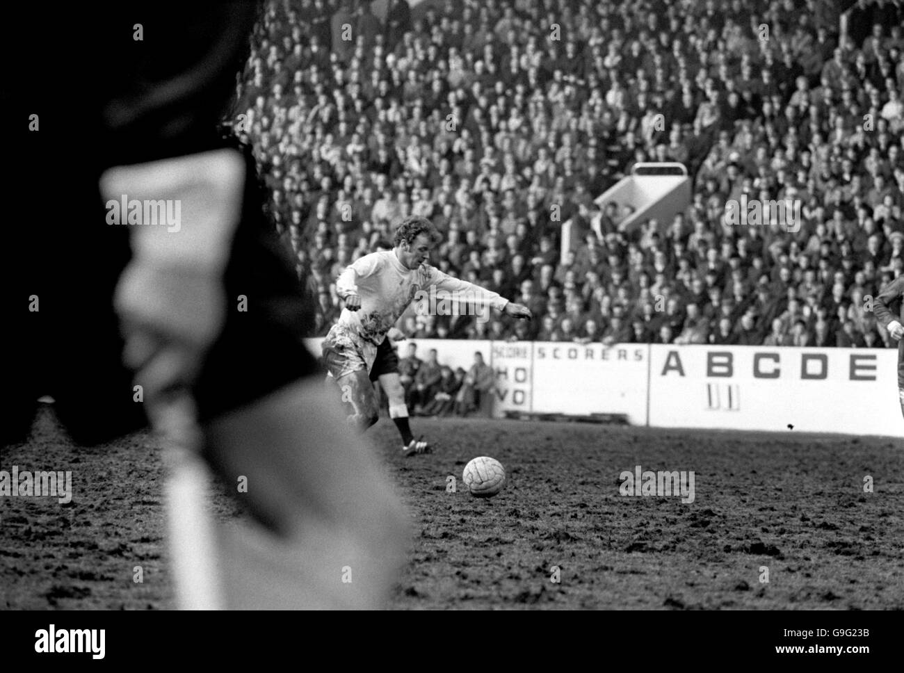 Il Billy Bremner di Leeds United, parzialmente oscurato dalla gamba del linesman, allinea un tiro al traguardo Foto Stock