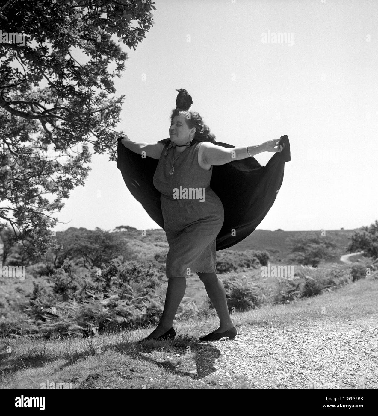 Con il suo jackdaw Hotfoot Jackson arroccato sulla sua testa, Sybil Leek, la "Strega Bianca di Burley", si stende il mantello in una danza rituale nella New Forest. Alta sacerdotessa di un coven di 13 streghe, ha fornito un servizio di incantesimo-casting e di erbe-healing per i clienti in tutto il paese. Foto Stock