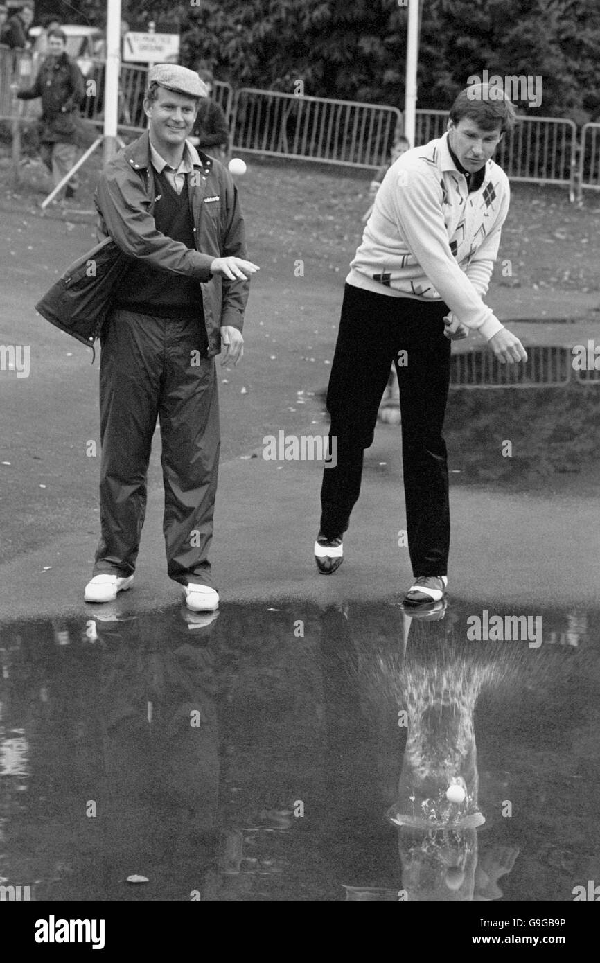 (L-R) i finalisti Sandy Lyle e Nick Faldo provano a skimming di palline da golf in uno dei tanti pozzanghere di Wentworth, dove il gioco è stato rinviato a causa della pioggia torrenziale Foto Stock