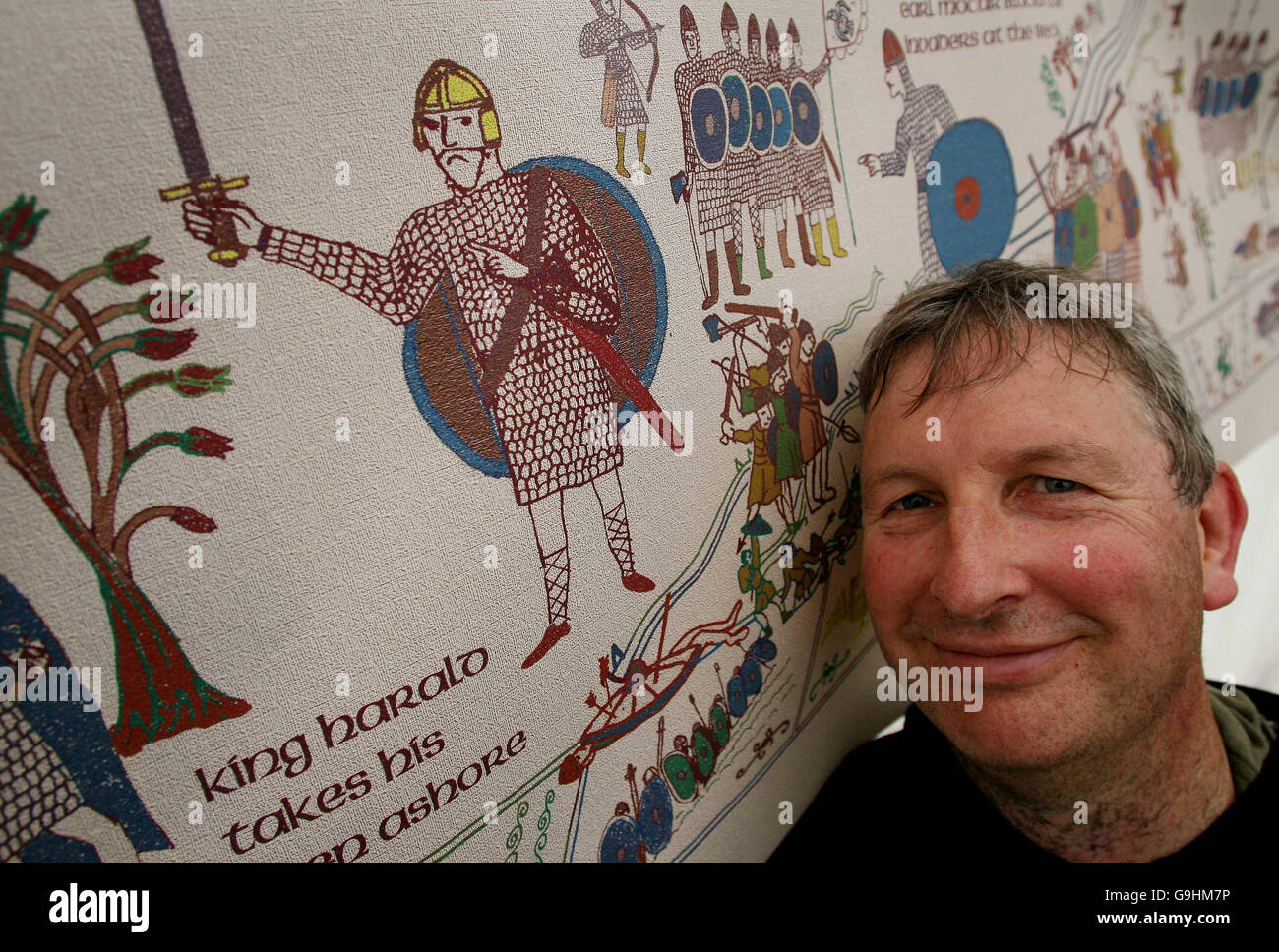 Chas Jones, coordinatore della Prefazione dello Yorkshire all'Arazzo di Bayeux, con una stampa di ciò che l'ultimo pezzo sarà simile prima del più grande mai ri-enactment della Battaglia di Hastings a Battle Abbey, Battle, East Sussex. Foto Stock