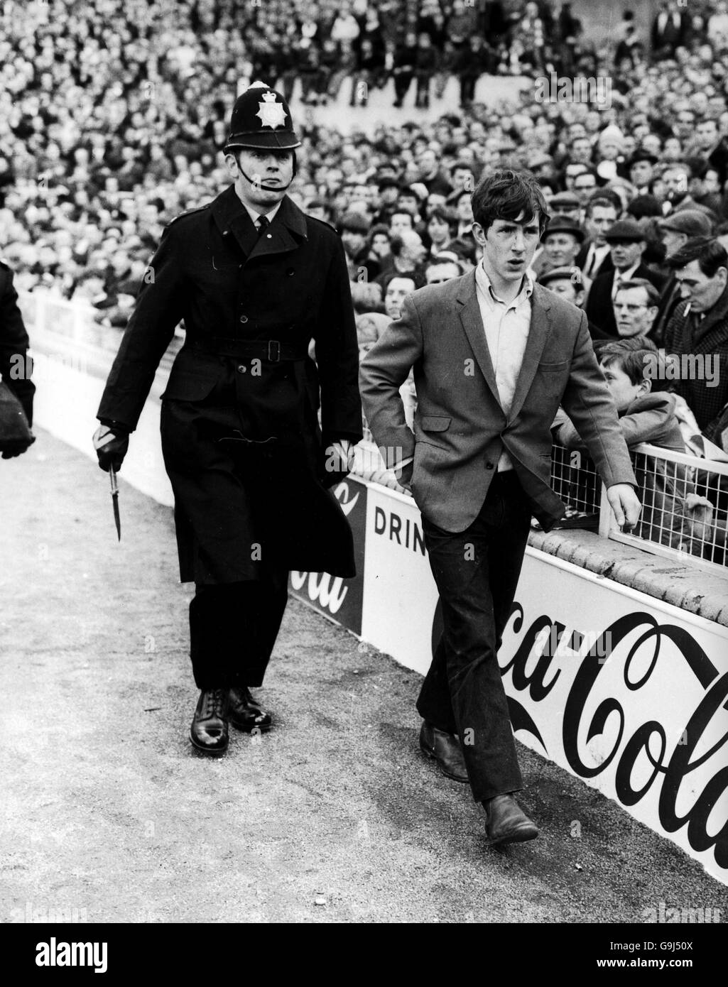 Un fan di Millwall viene scortato da terra dopo che un poliziotto gli ha confiscato un coltello da pugnale (l'articolo offendente può essere visto nella mano destra del conestabile) Foto Stock