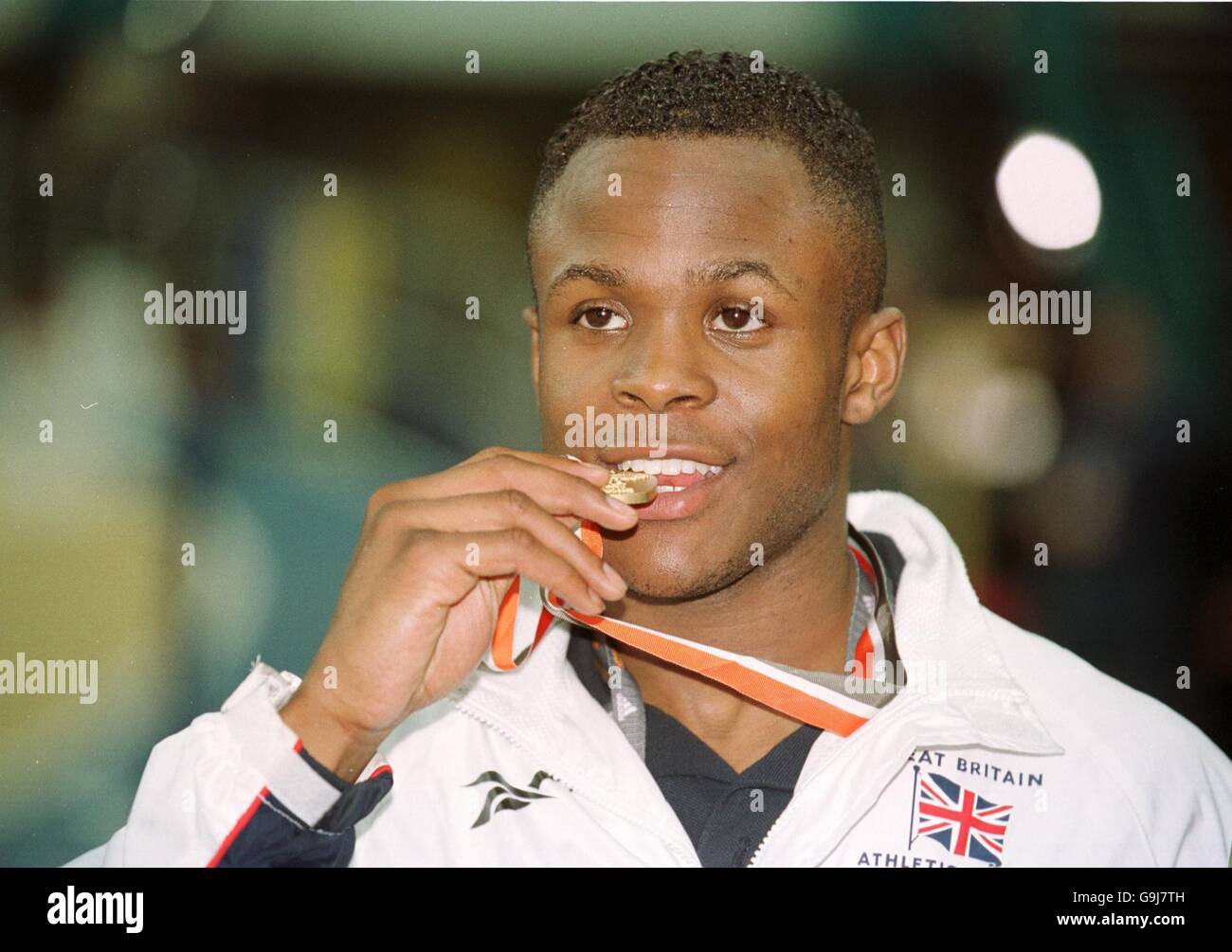 Atletica - Campionati mondiali indoor IAAF 2001 - Lisbona. Daniel Caines della Gran Bretagna morde la sua medaglia d'oro dalla finale dell'evento maschile di 400m come la realtà della situazione affonda dentro Foto Stock