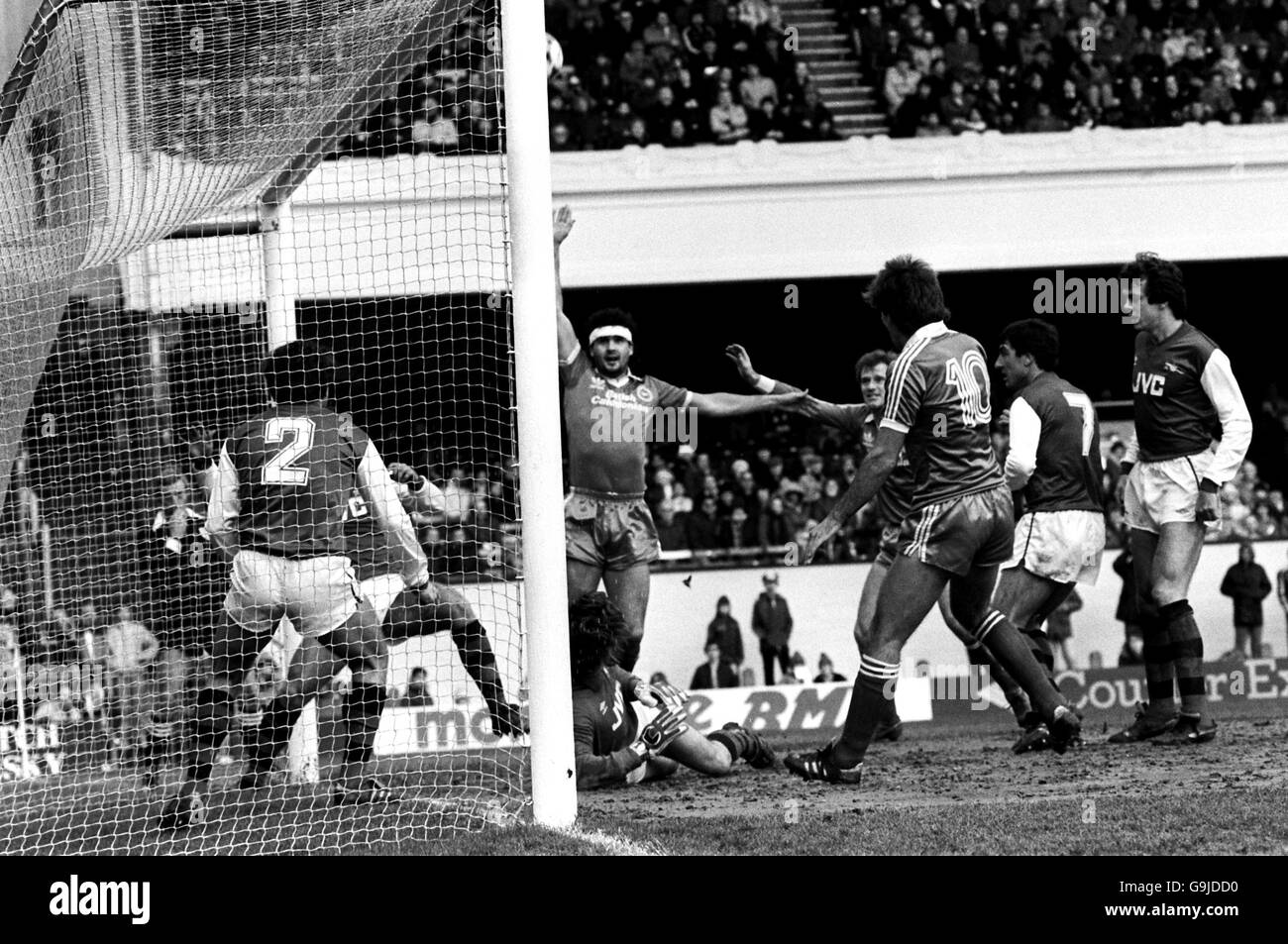 Steve Foster (c) di Brighton e Hove Albion inizia a celebrare un traguardo, ma, fortunatamente per l'Arsenal, la palla è già in via di passaggio sul bar Foto Stock
