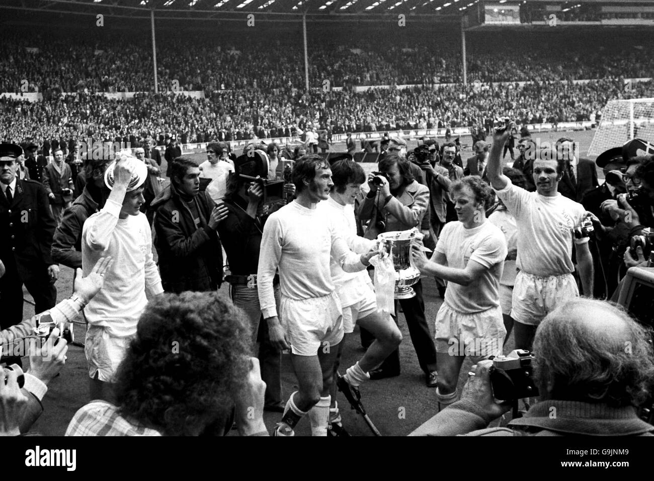 (L-R) la stampa circonda Allan Clarke, Paul Madeley, Eddie Grey, Billy Bremner e Paul Reaney di Leeds United mentre festeggiano con la fa Cup sul giro d'onore della loro squadra Foto Stock