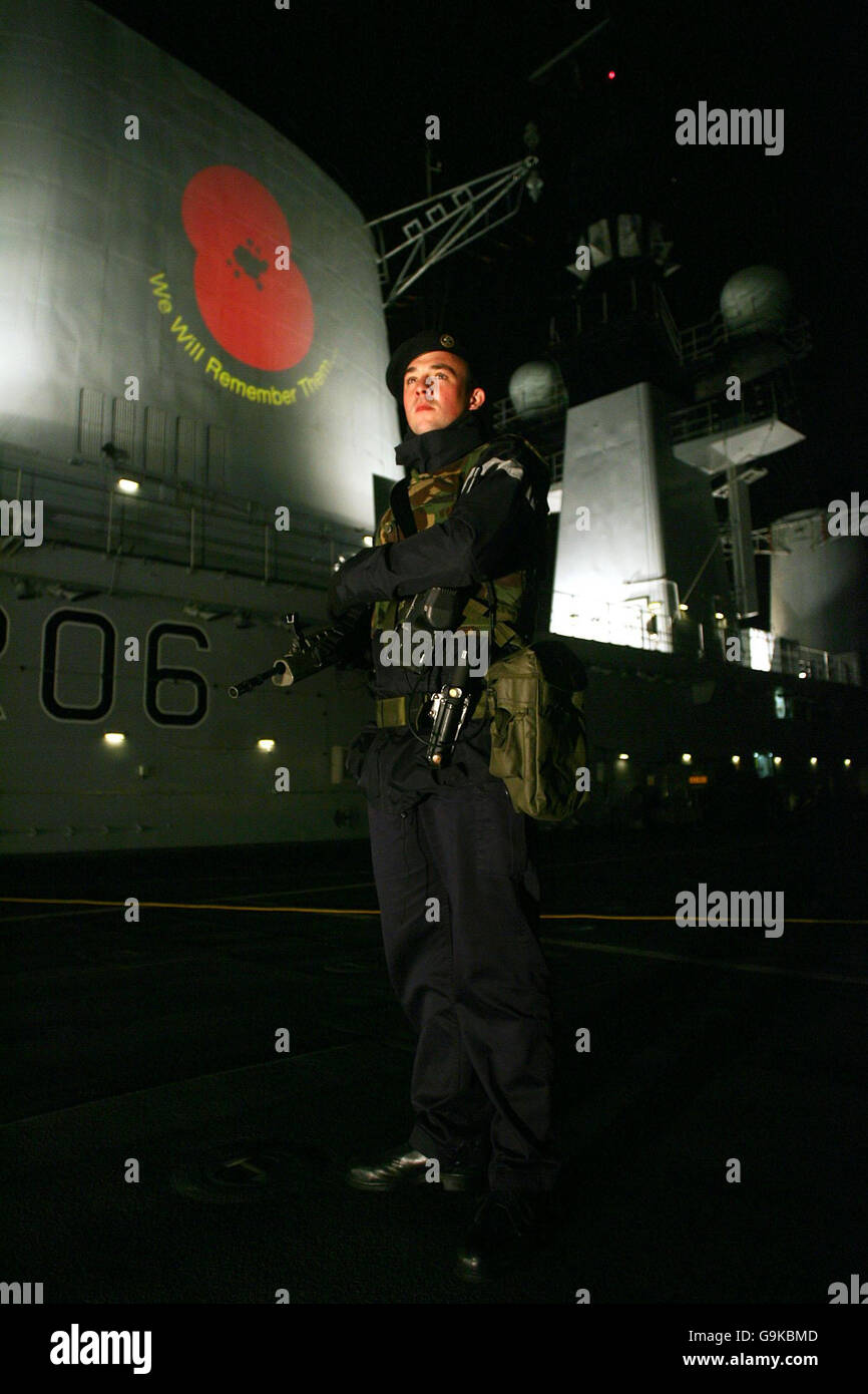 L'ONC David Lansley si erge a bordo dell'HMS Illustrious, mentre un papavero viene proiettato sulla nave per celebrare il giorno della memoria, mentre ormeggiato a Greenwich, Londra. Foto Stock