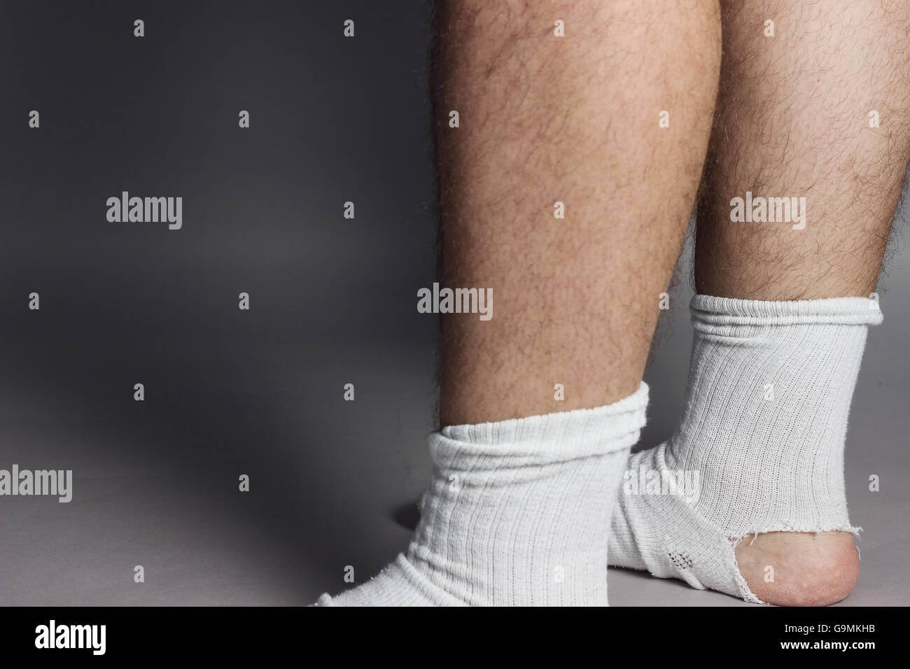 In piedi piedi con calze bianche e un grande foro nella parte anteriore di uno sfondo grigio Foto Stock