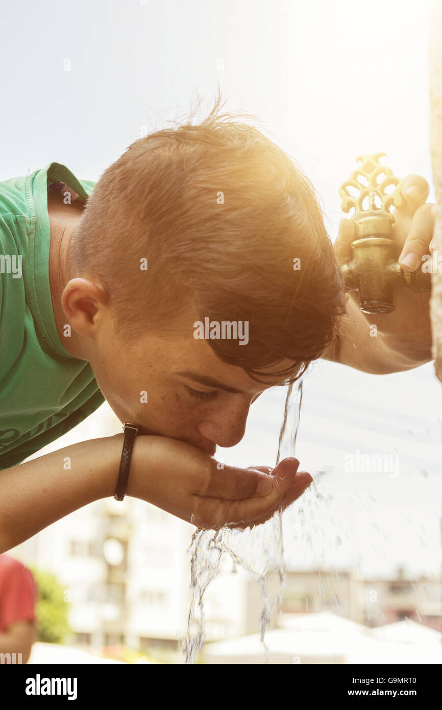 Ragazzo di bere acqua dal rubinetto orientali nella città di Prizren Foto Stock