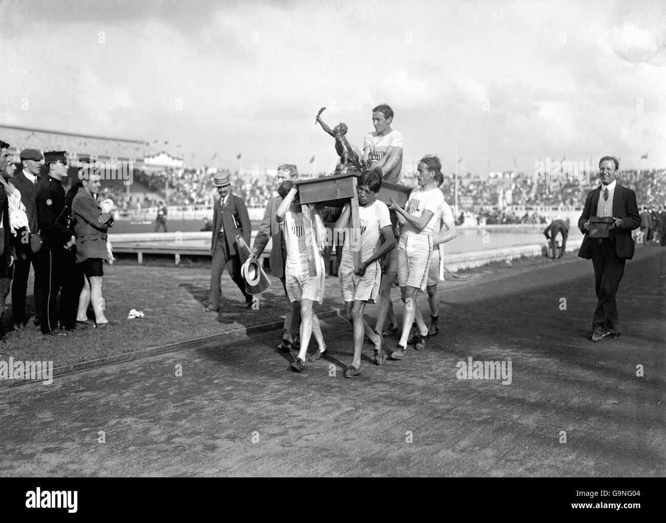John Hayes degli Stati Uniti, medaglia d'oro nella maratona, mostra il suo trofeo mentre viene trasportato intorno allo stadio di White City su un tavolo da compagni di squadra Foto Stock