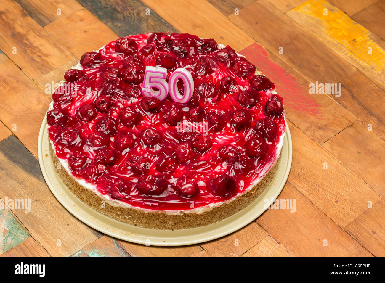 Cherry cheese cake con candele per il cinquantesimo compleanno su una tavola di legno Foto Stock