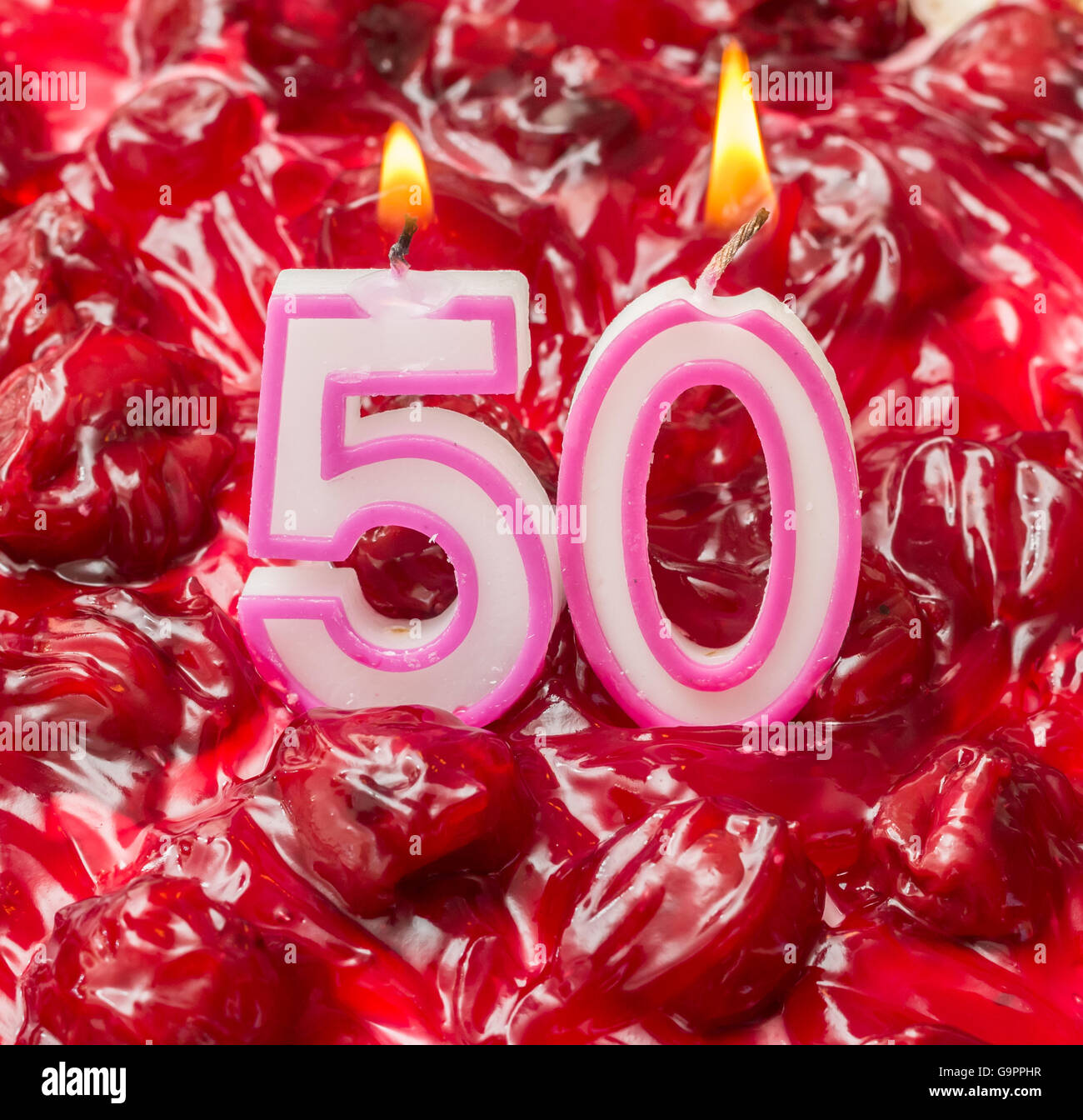 Cherry cheese cake con candele accese per il cinquantesimo compleanno Foto Stock