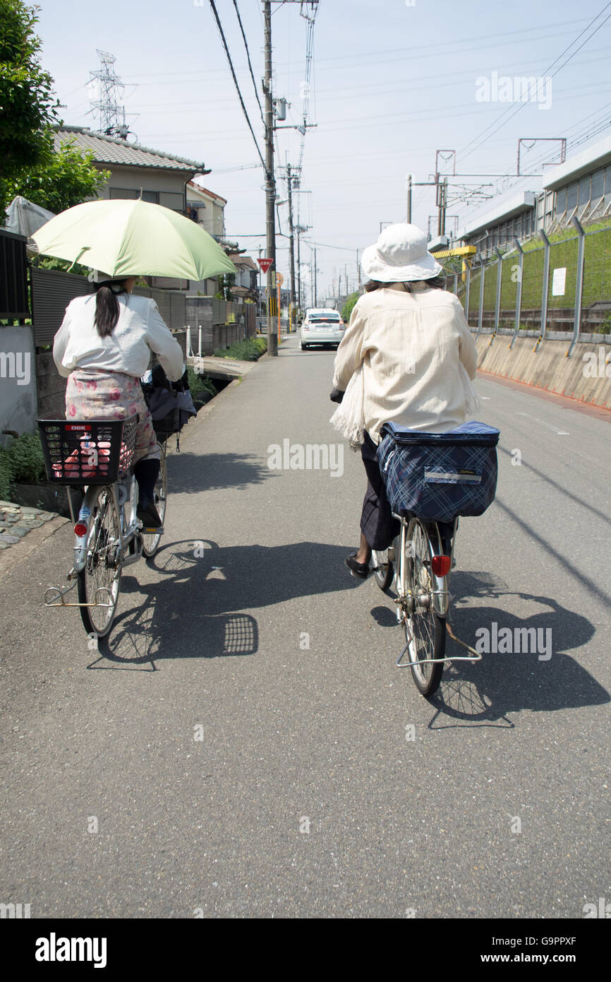Due femmina commuter ciclisti a Kyoto, in Giappone. Foto Stock
