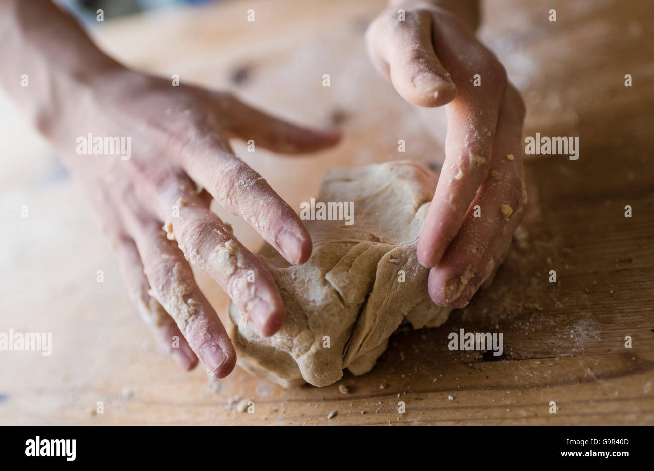 Close-up di due forti mani di un fornaio che sono manualmente gli impasti su una ruvida, cucina in legno tabella Foto Stock Close-up di due forti mani di un fornaio che sono manualmente gli impasti su una ruvida, cucina in legno tabella Foto Stock