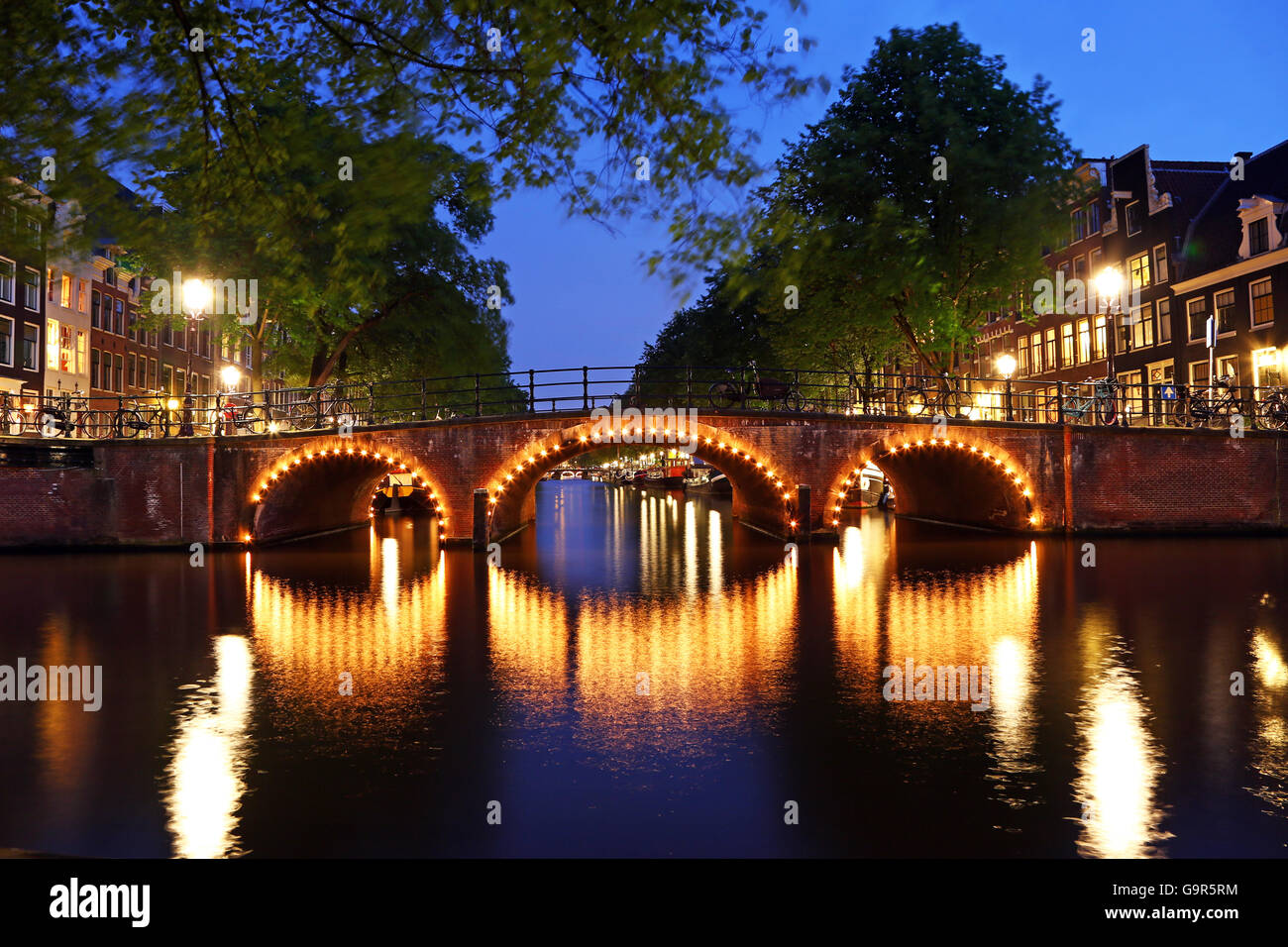 Illuminato il ponte sul canale di notte sul canale tra Prinsengracht e Brouwersgracht in Amsterdam, Olanda Foto Stock