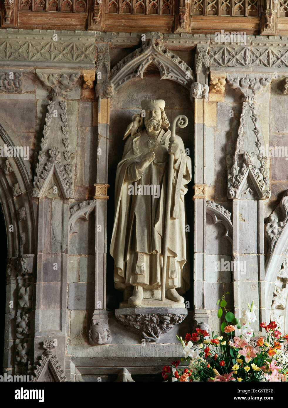 Moderna statua di St David (Dewi Sant), patrono del Galles, collocata in una nicchia su una C XIV schermata di pietra in St David's Cathedral, Pembrokeshire. Foto Stock