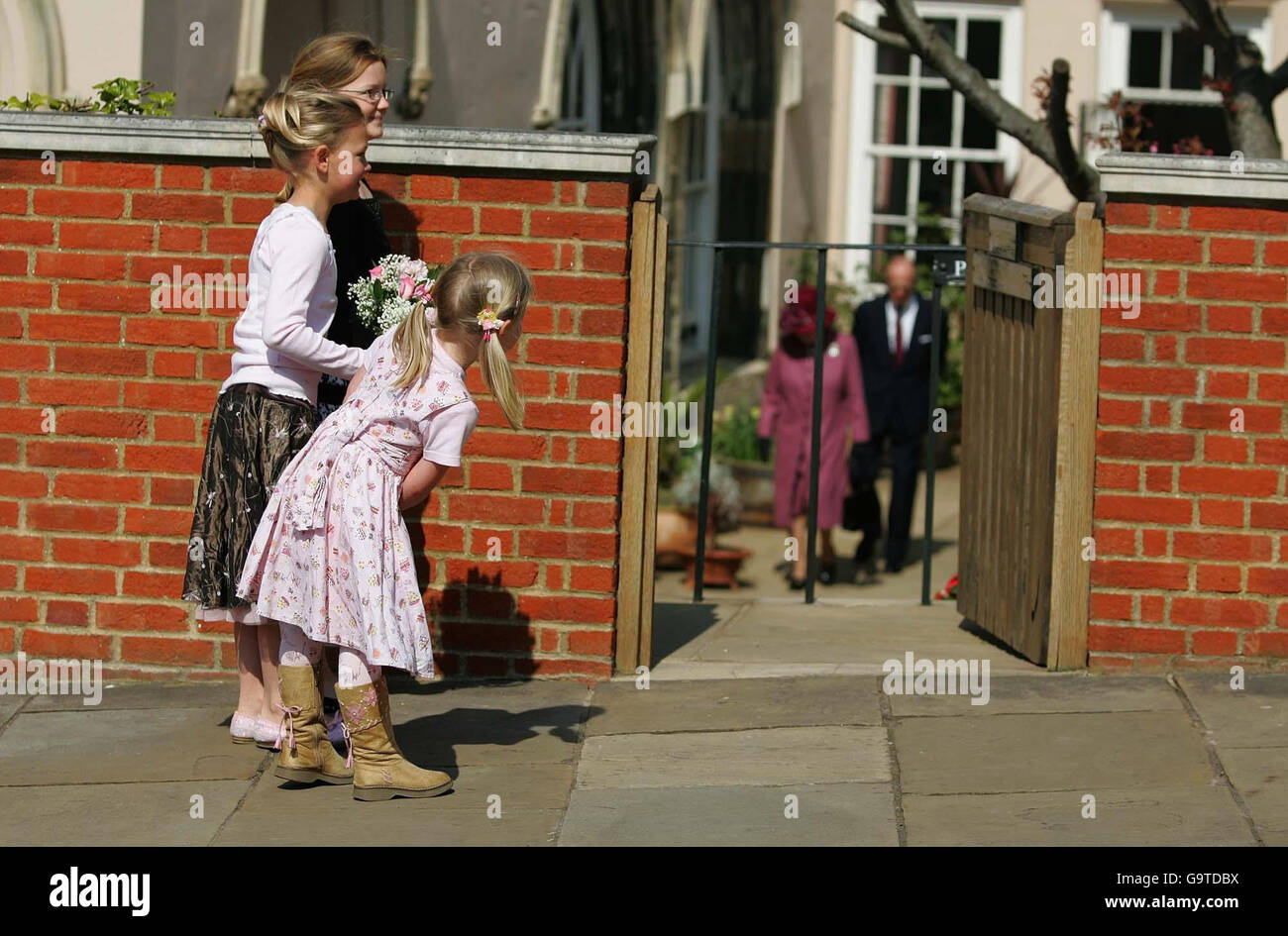 Maddie Gainer, 5 anni, con le sue sorelle Natasha, 10 anni, e Abigail, 8, si intravedono intorno al muro per dare un'occhiata alla regina Elisabetta II e al duca di Edimburgo mentre lasciano il servizio della domenica di Pasqua nella cappella di San Giorgio, Castello di Windsor. Foto Stock