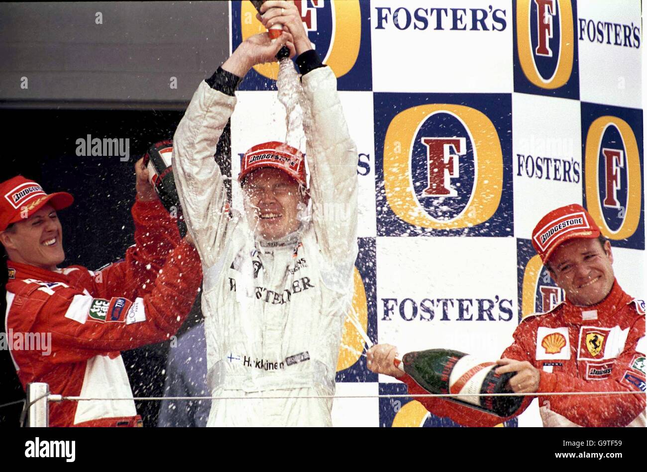 Michael Schumacher e Rubens Barrichello spruzzano Mika Hakkinen con champagne Dopo ha vinto il Gran Premio di Gran Bretagna Foto Stock