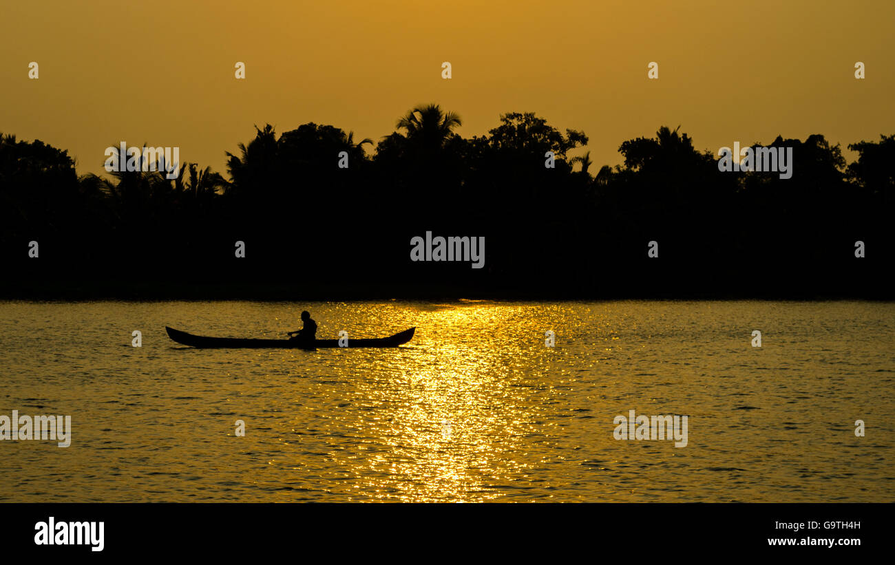 Silhouette di una barca su un fiume al tramonto Foto Stock