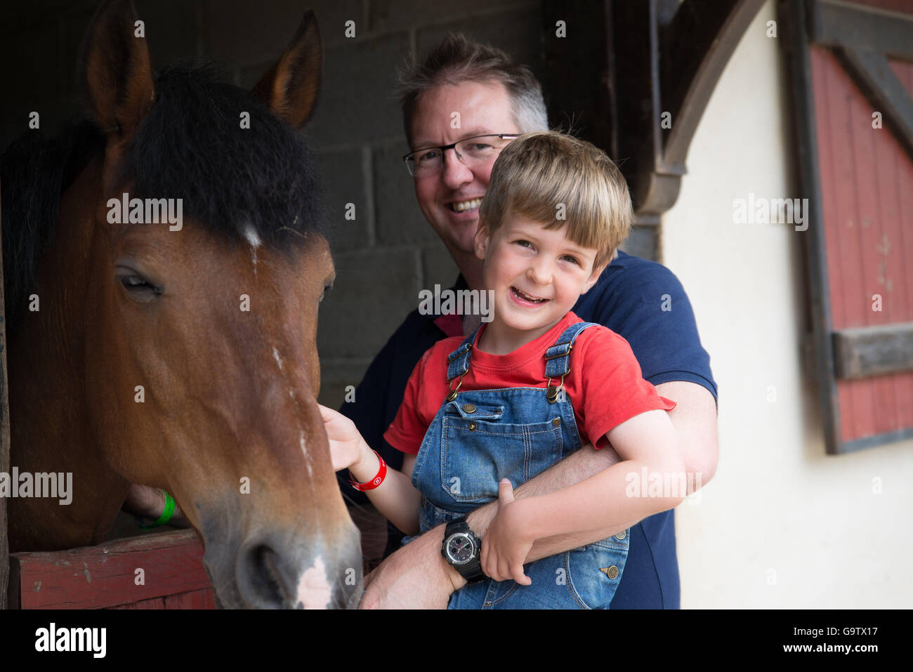 Padre e figlio a cavallo a stabile a Eurocamp a Dol De Bretagne in Bretagna Foto Stock