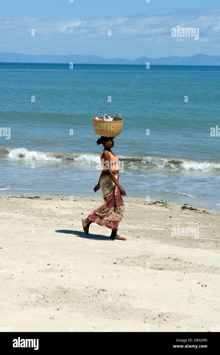 Donna locale a Nosy Be beach portando un cesto sulla sua testa, isola di Nosy Be, Madagascar, Africa / Nosy Be Foto Stock