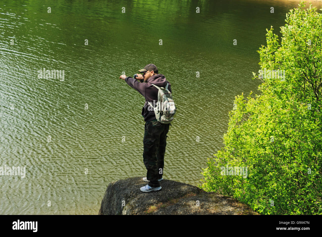 Uomo su una roccia sopra l'acqua in una posizione per passare Foto Stock