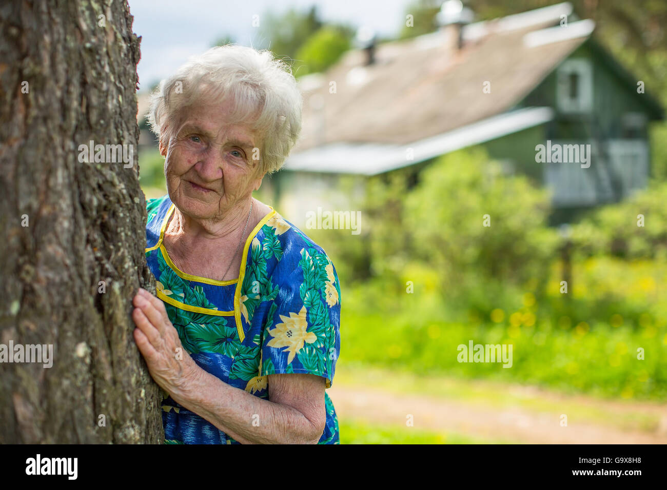 Una donna anziana vicino alla sua casa nel villaggio. Foto Stock