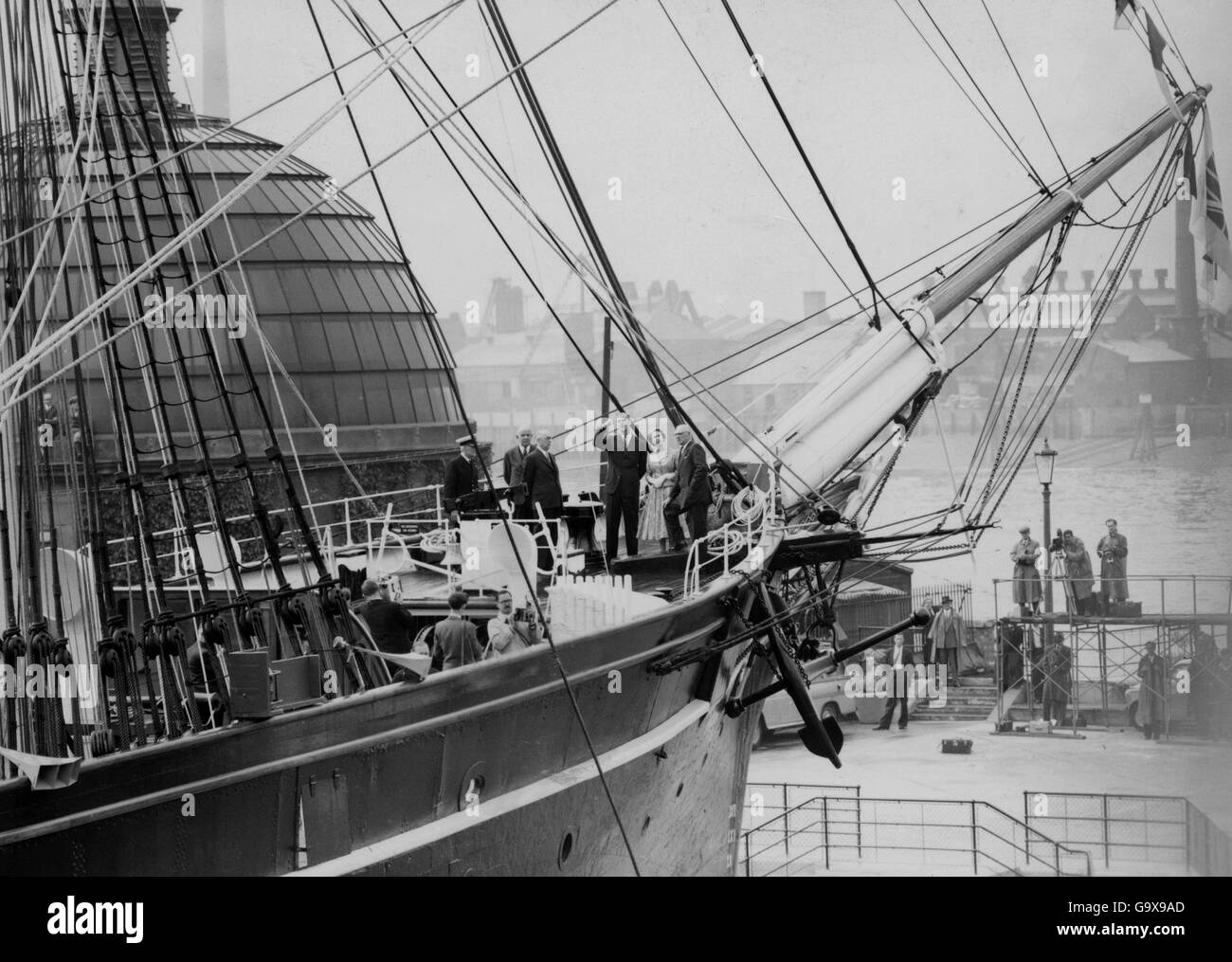 In piedi negli archi della nave il suo visitatore reale - la Regina Elisabetta II, che 'aprì' la nave al suo ormeggio permanente vicino al Museo Marittimo Nazionale a Greenwich, Londra. La regina, che fu accompagnata dal duca di Edimburgo (guardando verso l'alto il rigging), salì a bordo del Clipper e fece un giro della nave. Cutty Sark, una volta la nave più veloce della corsa in Cina, è stato istituito come un tributo alla Marina mercantile e ai giorni della vela. Foto Stock