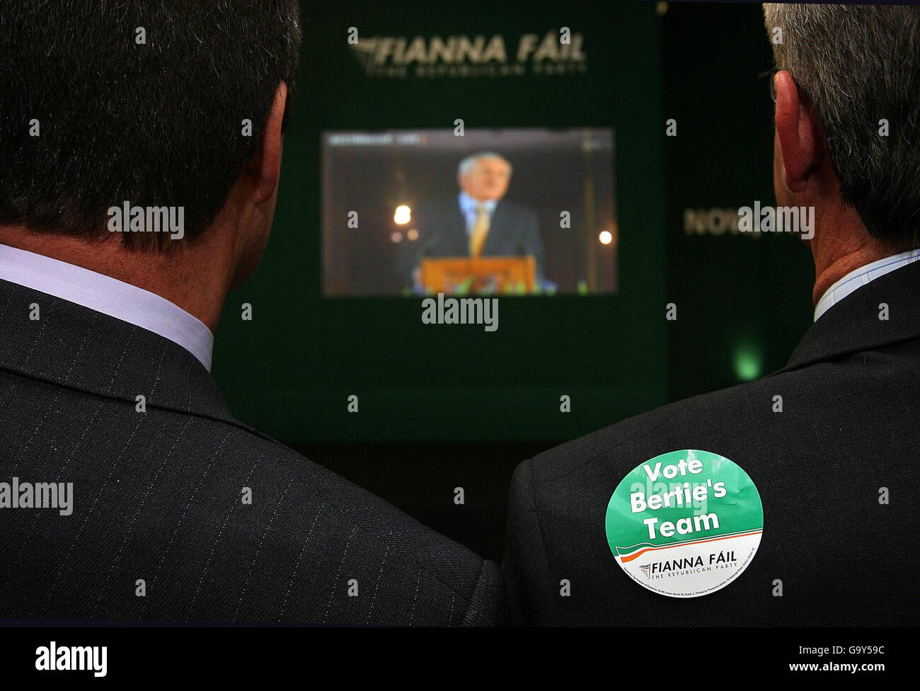 I sostenitori del partito guardano a Taoiseach e al leader del partito Fianna Fail Bertie Ahern che hanno inviato un discorso storico alle Houses of Parliment di Londra, tramite un collegamento video presso la sede centrale del suo partito a Dublino. Foto Stock