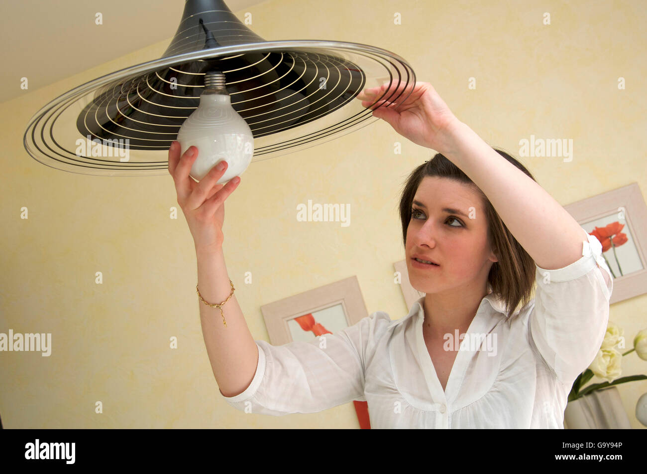 Donna cambiare una lampadina elettrica Foto stock - Alamy