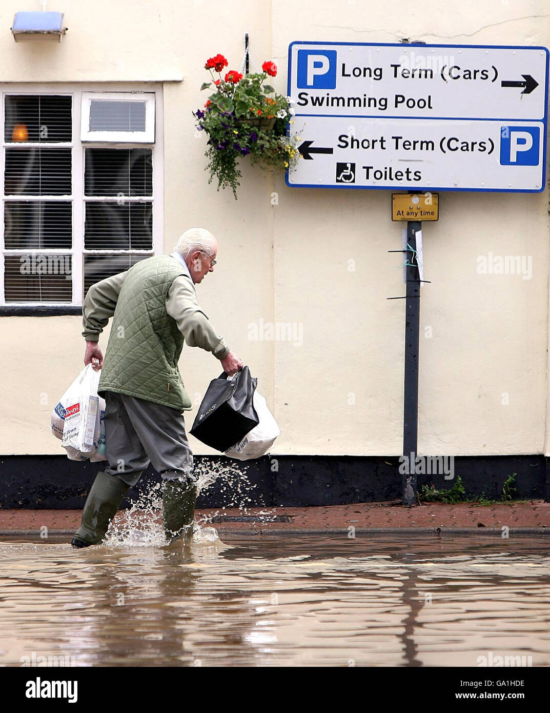 Un residente locale lotta attraverso le inondazioni sulla High Street a Tenbury Wells, Worcestershire. Foto Stock