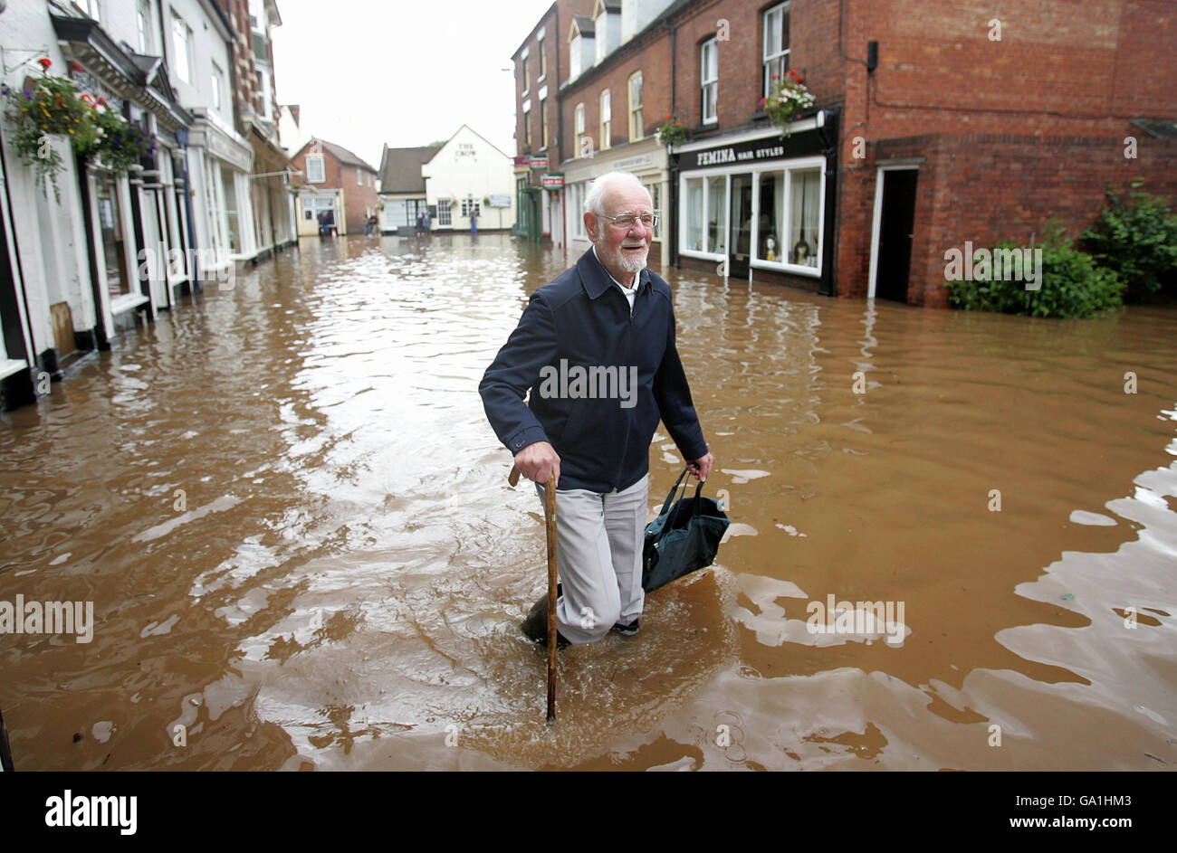 Un residente locale cerca di arrivare lungo Market Street a Tenbury Wells, inondato dal fiume Teme. Foto Stock