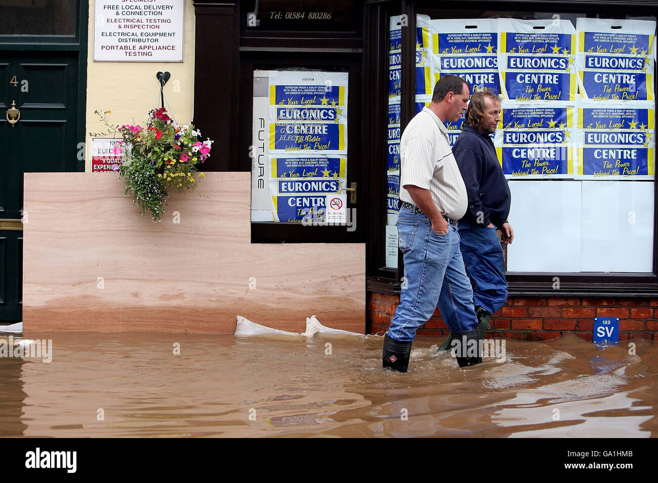 Le inondazioni colpiscono la Gran Bretagna. I residenti locali si fanno strada lungo Market Street a Tenbury Wells, inondato dal fiume Teme. Foto Stock