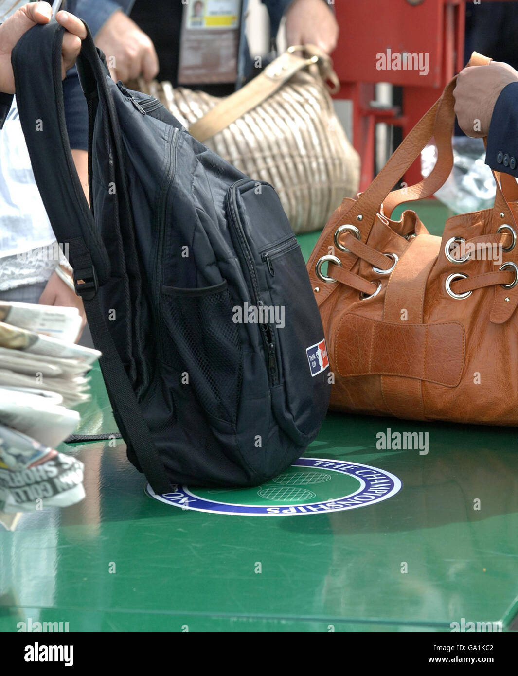 Le borse vengono ricercate al cancello uno quando i fan arrivano per l'All England Lawn Tennis Championship a Wimbledon. Foto Stock