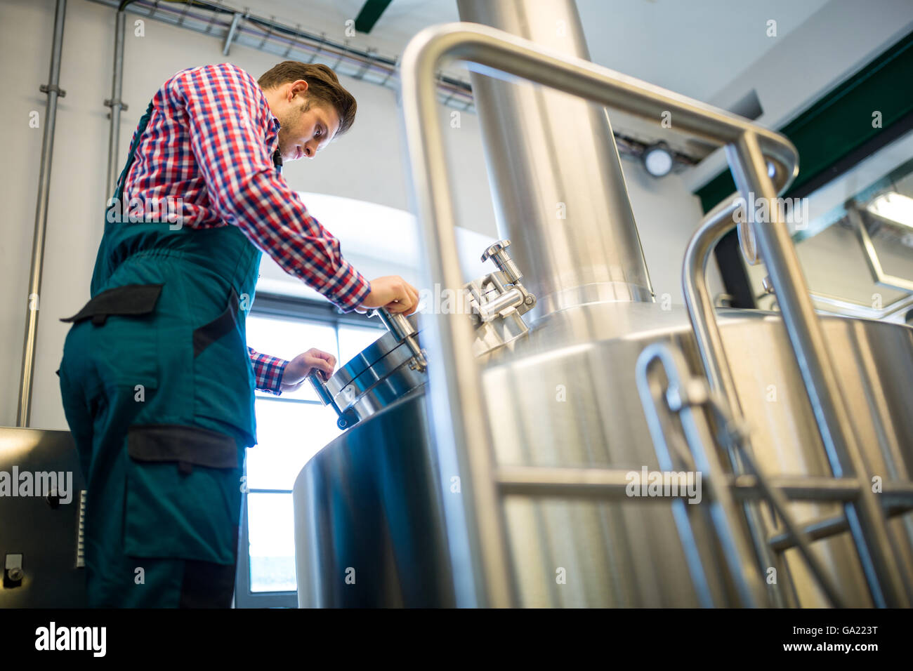Lavoratore di manutenzione a lavorare presso la fabbrica di birra Foto Stock