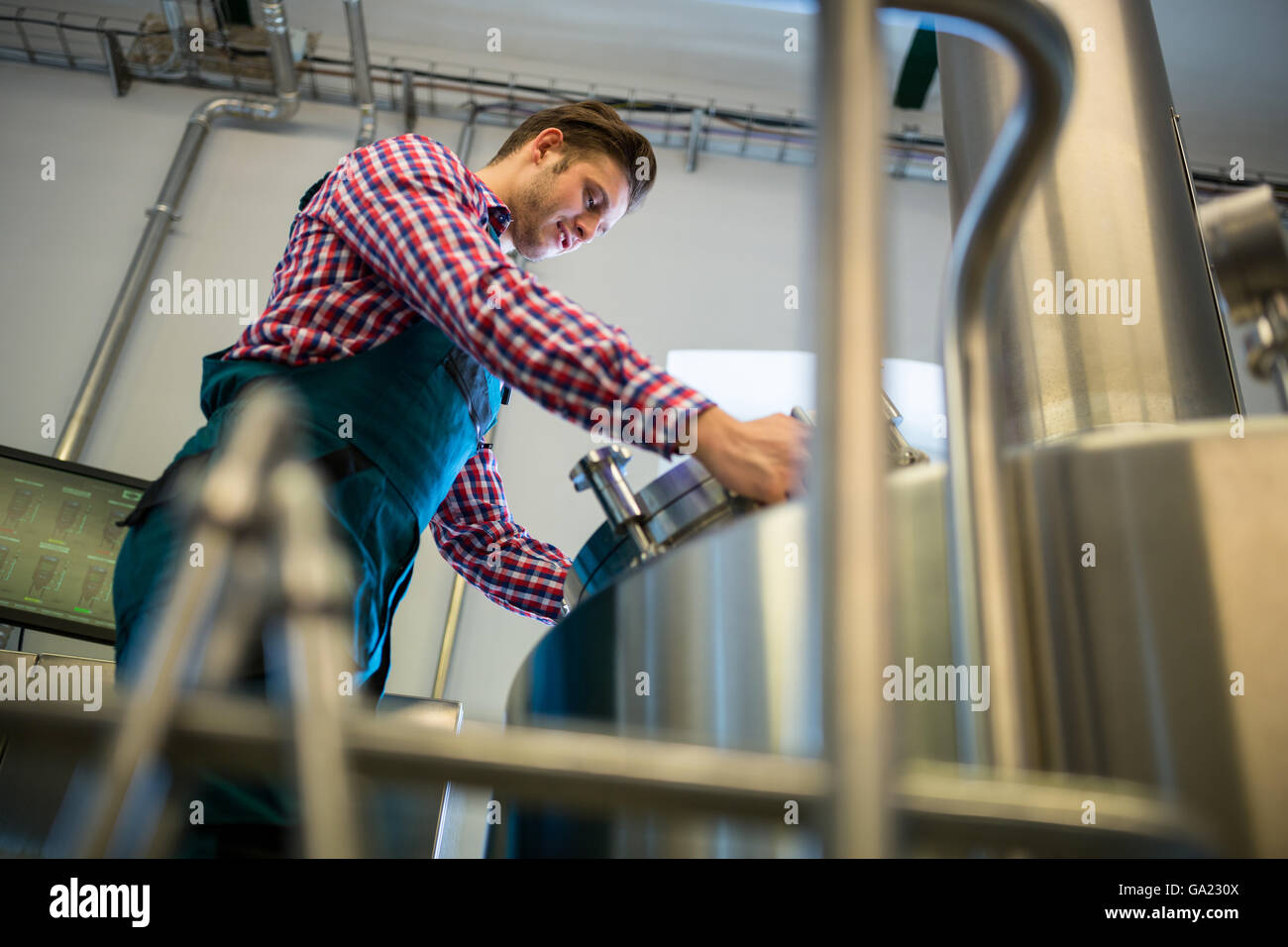Lavoratore di manutenzione a lavorare presso la fabbrica di birra Foto Stock
