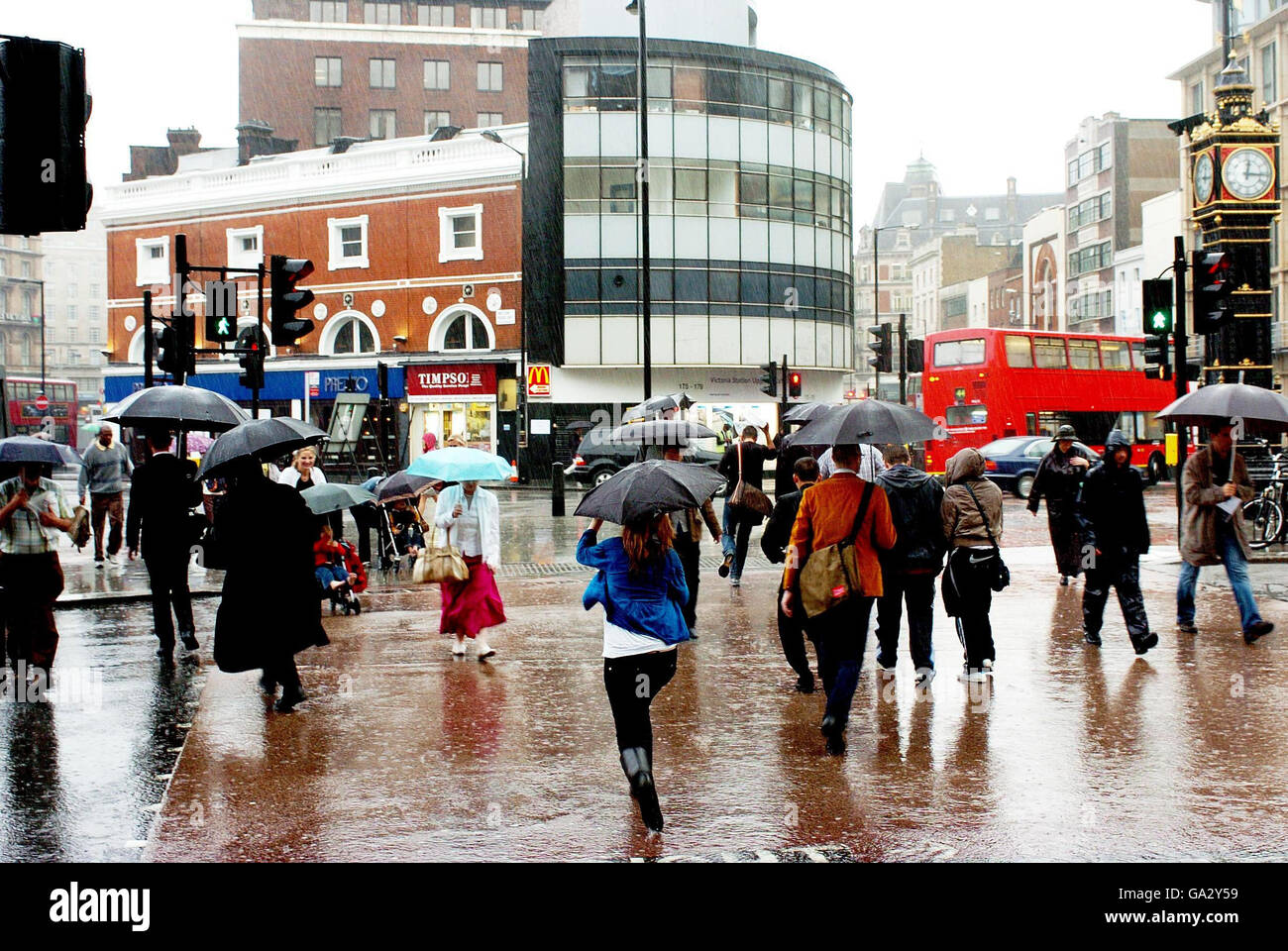 Tempeste per colpire il Regno Unito. I pendolari attraversano una strada di Londra durante una doccia pesante. Foto Stock