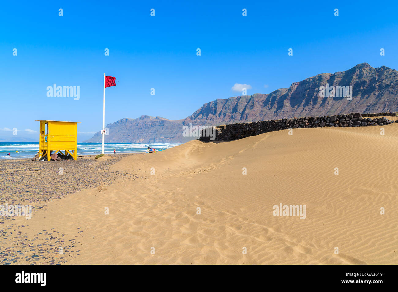 Dune di sabbia e giallo stand bagnino sulla spiaggia di Famara, famoso luogo di surf sulla isola di Lanzarote, Spagna Foto Stock
