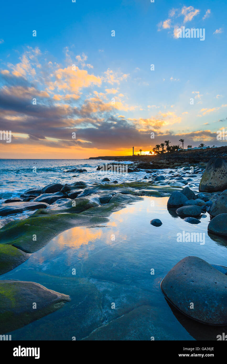 Pietre in acqua dell'oceano al tramonto in Playa Blanca sull isola di Lanzarote, Spagna Foto Stock