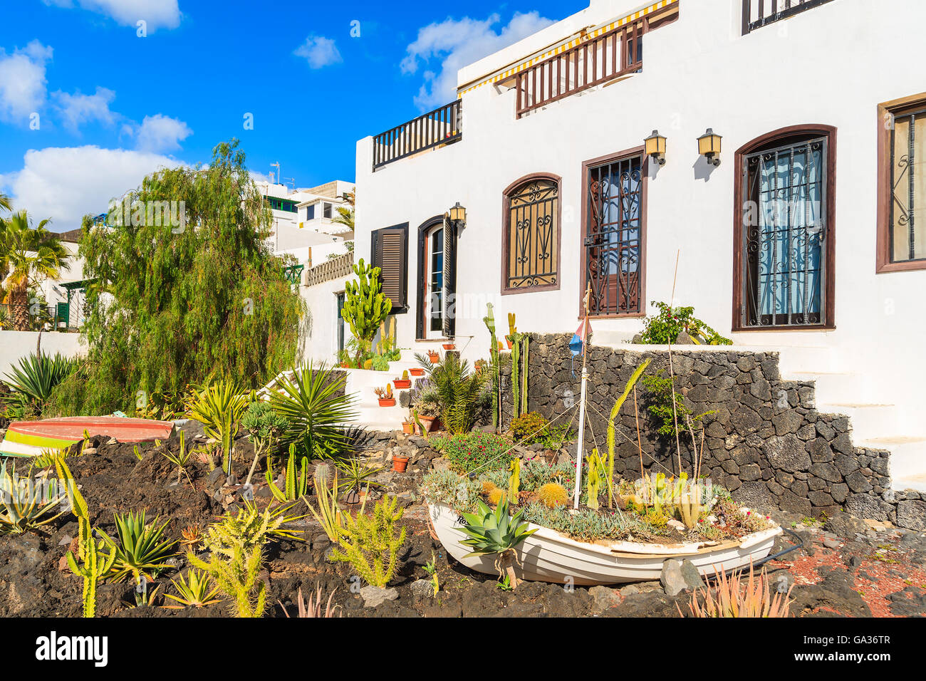 Barca da pesca nel giardino della tipica canaria case in Puerto del Carmen città sulla costa dell'isola di Lanzarote, Spagna Foto Stock