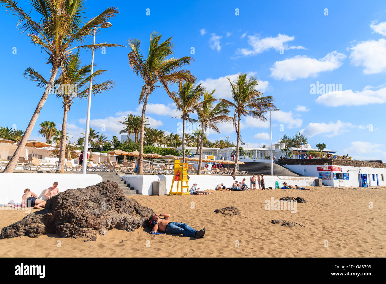 Spiaggia di Puerto del Carmen, Lanzarote Island - Jan 17, 2015: spiaggia tropicale con palme in Puerto del Carmen town. Le isole Canarie sono destinazione di vacanza popolare tra i turisti europei. Foto Stock