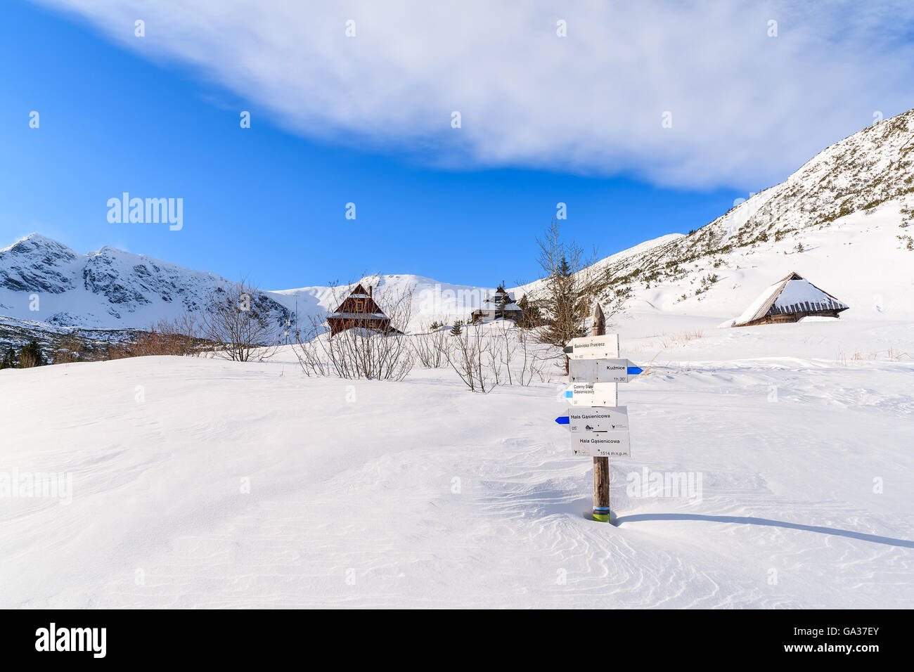 Sentiero di montagna segno sepolto nella neve in valle Gasienicowa con capanne in distanza, Monti Tatra, Polonia Foto Stock