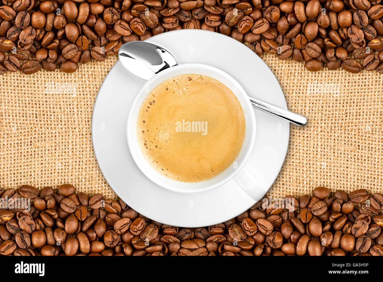 I chicchi di caffè e la tazza su sfondo di iuta Foto Stock