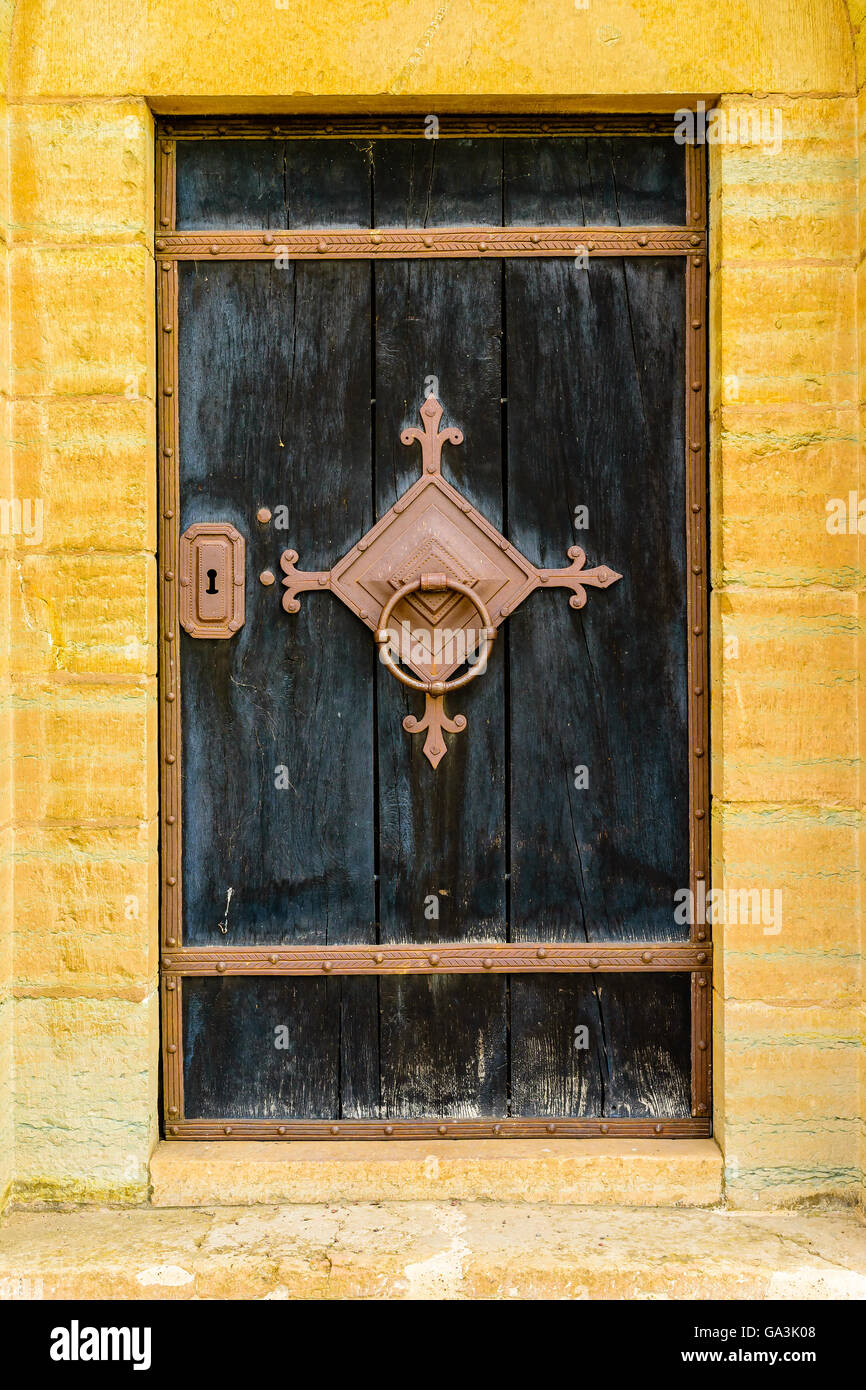 Molto vecchia porta di legno in nero con ferro arrugginito e bloccaggio maniglia. Foto Stock