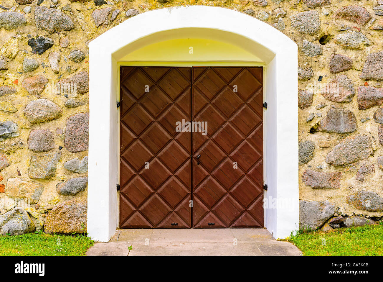 Vecchia porta di legno in marrone con semplice serratura e la maniglia. I muri in pietra che circonda la porta. Foto Stock