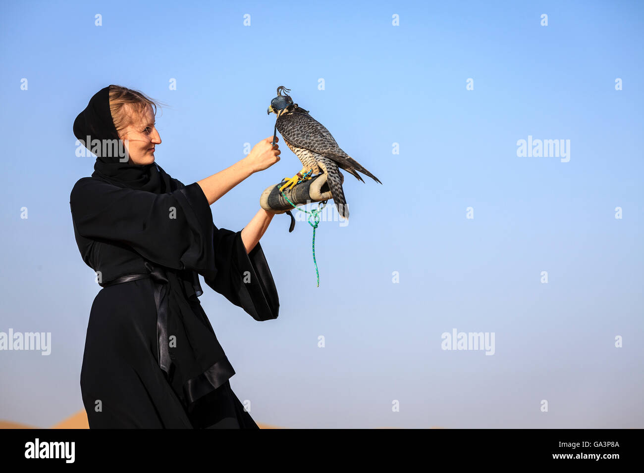 Giovane donna in abaya con falco pellegrino in Dubai Desert Conservation Reserve, EMIRATI ARABI UNITI Foto Stock