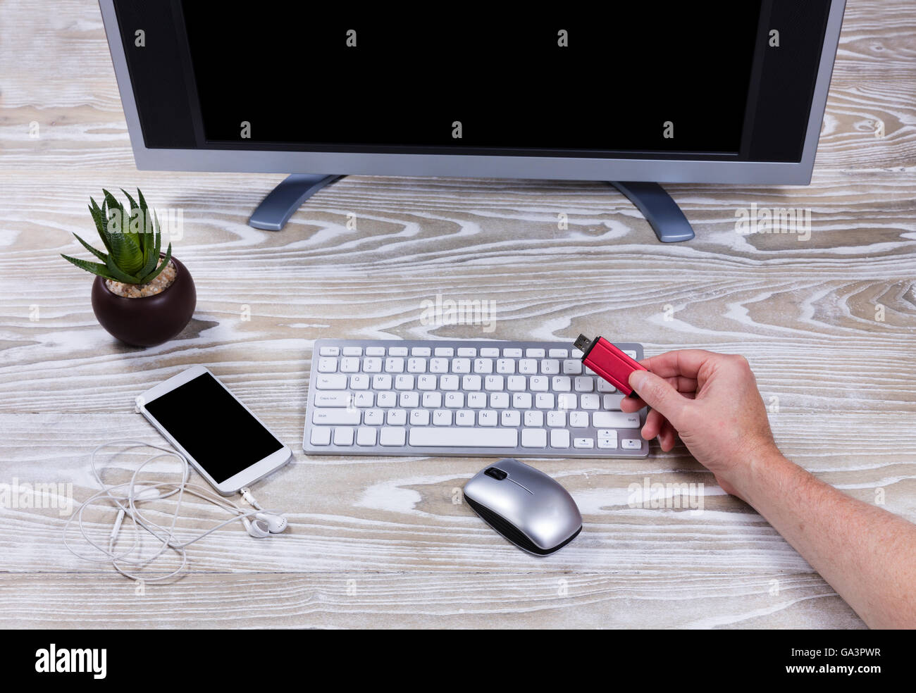 Vista aerea di lavoro desktop con la mano che regge lo storage dei dati thumb drive. Foto Stock