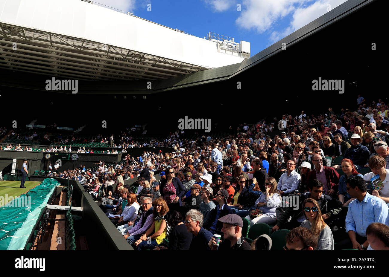 Gli spettatori iniziano a riempire centre court il giorno sette dei campionati di Wimbledon al All England Lawn Tennis e Croquet Club, Wimbledon. Foto Stock