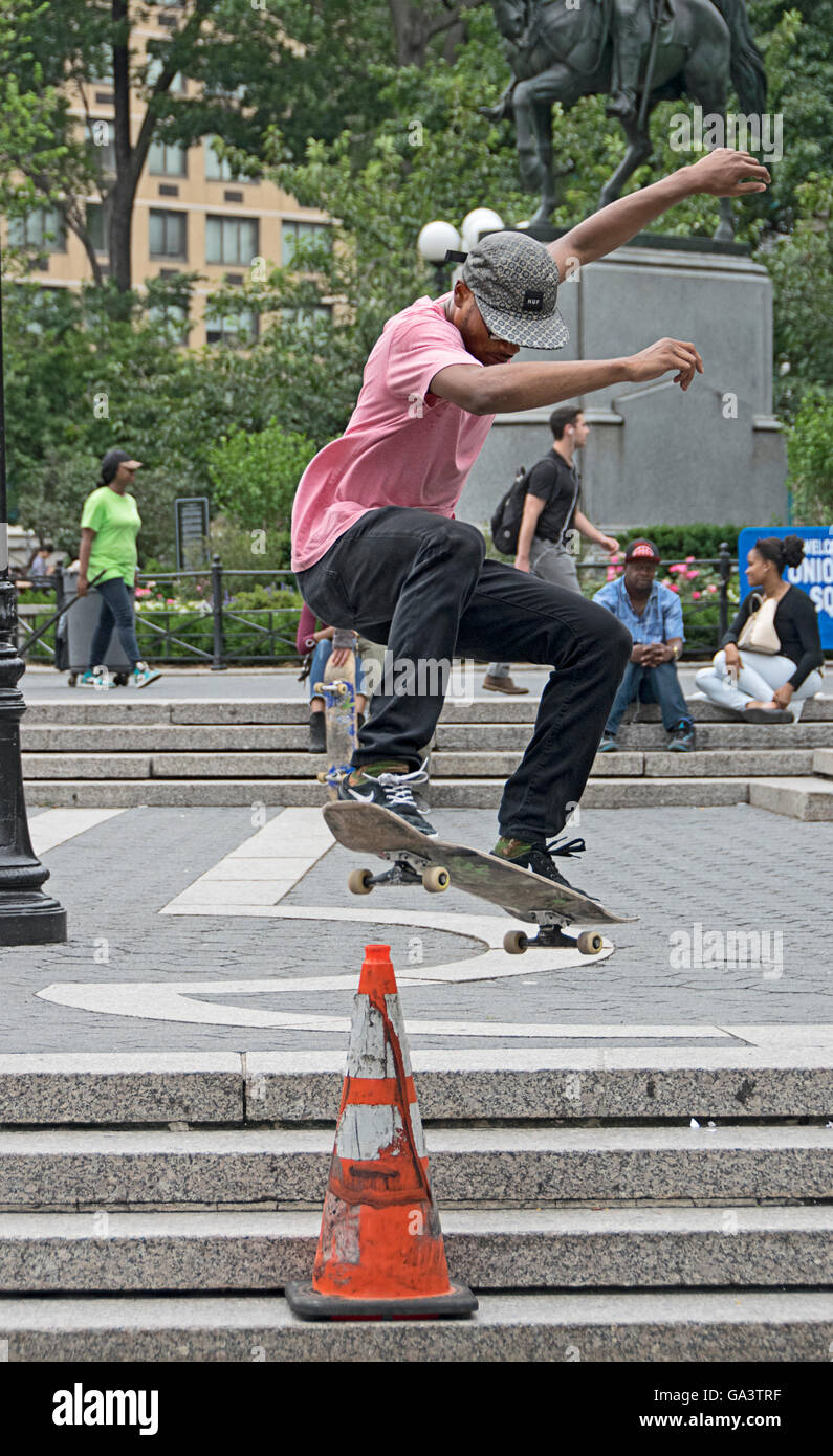 Skateboarders praticando salta sopra traffico coni in Union Square Park a New York City Foto Stock