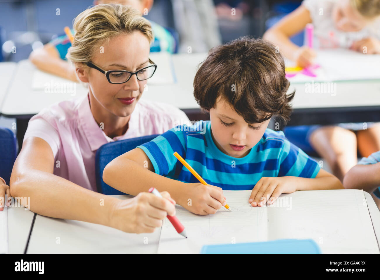 Docente Aiutare un ragazzo con studi in aula Foto Stock