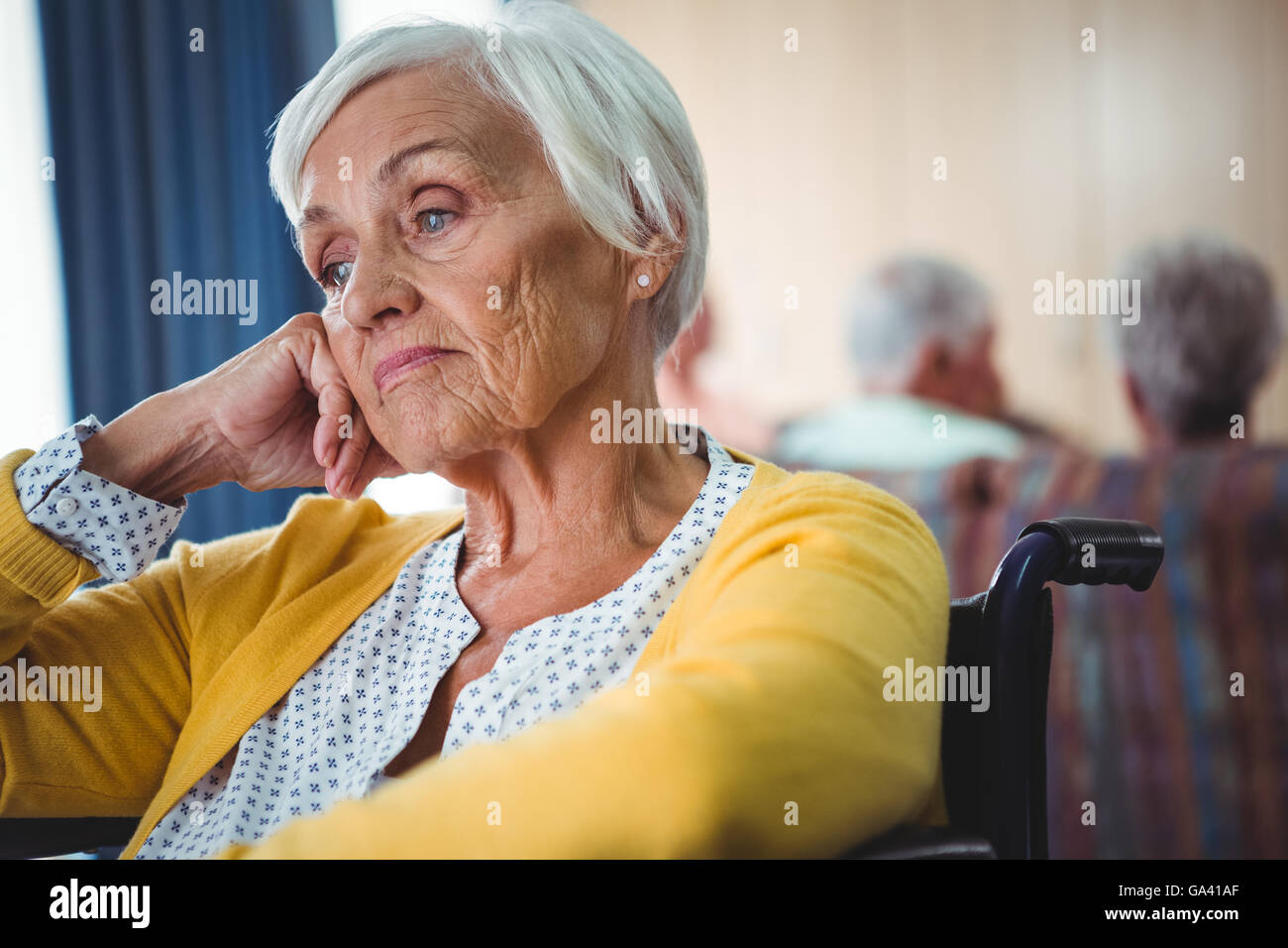 Senior donna in carrozzella sguardo preoccupato Foto Stock